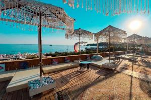 a deck with tables and umbrellas on the beach at Oyster Residences - Adult Only in Oludeniz