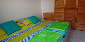 Un dormitorio con una cama con sábanas verdes y amarillas. en Apartmán Lentilka Senec, en Senec