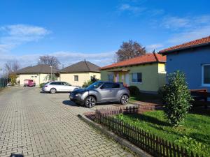 Dos coches aparcados en una entrada frente a las casas. en Apartmán Lentilka Senec, en Senec