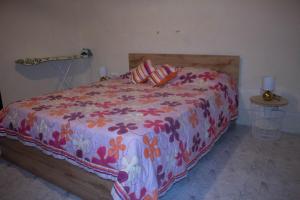 a bedroom with a bed with a floral comforter at Timeless Mqabba Heritage Home in Mqabba