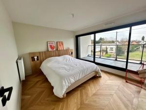 a bedroom with a bed and a large window at Villa Stella-plage proche Le Touquet pour 8 personnes in Cucq