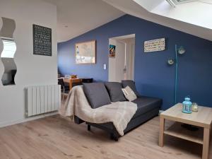 a living room with a couch and a blue wall at St Marc proche plage, 2 chambres in Saint-Nazaire