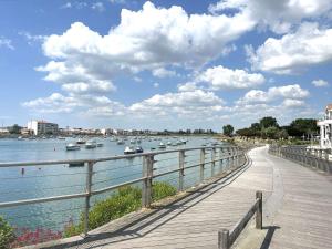 a wooden boardwalk next to a river with boats at Appartement 2 pièces avec parking privé, proche plage et commerces, Saint-Gilles-Croix-de-Vie - FR-1-224-783 in Saint-Gilles-Croix-de-Vie