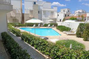 a swimming pool with an umbrella next to a building at Lucrezia - Relax, Piscina, Barbeque e Wi-Fi in Nardò