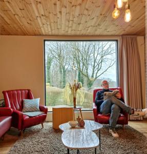 フーフェルラントにあるAppartement met terras 2 - 8 gasten Heuvelland Rodebergの居間の赤い椅子に座る男
