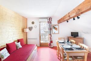 un soggiorno con un tavolo e un divano rosso di À 200m des pistes de ski, appartement pour 4 a La Joue du Loup