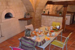 a woman is sitting at a table in a kitchen at Chambre Gargantua Le dolmen in Thizay