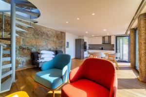a living room with two chairs and a staircase at Quinta de Casal do Bairro Casa do Alpendre in Guimarães