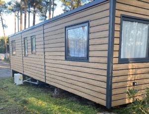 a log cabin with two windows on the side of it at MH 3CH à l'océan Landais chez Claiclé in Saint-Julien-en-Born