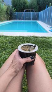 a person holding a cup of coffee in front of a pool at CASA QUINTA SICARDi lp in La Plata