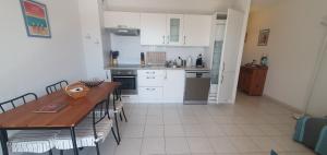 Una cocina con gabinetes blancos y una mesa y sillas. en appartement residence les vagues, en Soulac-sur-Mer 4 fotos más