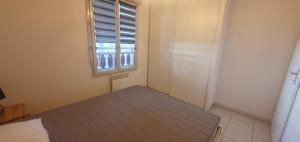 Una pequeña habitación con una cama y una ventana. en appartement residence les vagues, en Soulac-sur-Mer