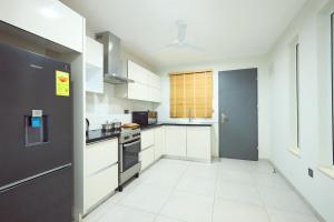 a kitchen with white cabinets and a stove top oven at Cozy 2-Bedroom behind West Hills Mall in New Weija