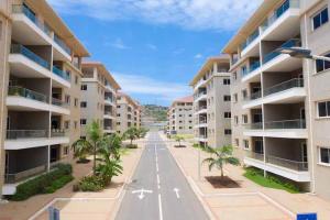 an empty street in front of apartment buildings at Cozy 2-Bedroom behind West Hills Mall in New Weija