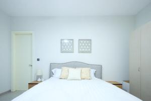 a white bedroom with a white bed with two pillows at Cozy 2-Bedroom behind West Hills Mall in New Weija
