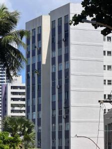 a tall white building with palm trees in front of it at 1101 Barra Salvador - Excelente para o Carnaval! in Salvador