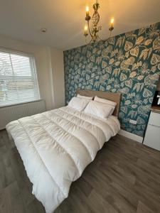 a large white bed in a bedroom with a wall at The Olivia Swan in Deighton
