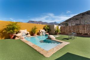 a backyard with a swimming pool and green grass at Vivienda Vacacional Folillo in La Aldea de San Nicolas