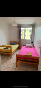 two beds in a room with a window at Appartement balcon, place de parking, centre ville in Valence