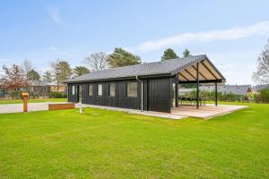 ein schwarzes Gebäude mit einem Pavillon in einem Park in der Unterkunft Beautiful And Modern 8-Person Holiday Home With Spacious Terraces And Quality Interiors Located In Peaceful Fuglslev Close To Forest, Nature And in Ebeltoft