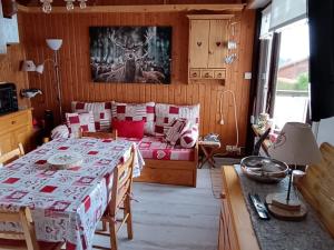 a living room with a table and a bed in a room at Appartement cosy proche pistes ski avec garage - FR-1-498-112 in Thollon