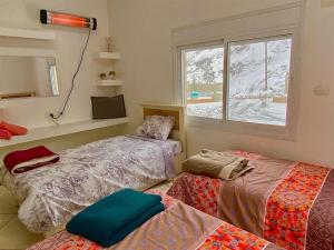a room with two beds and a window at Hermon Garden Apartment in Majdal Shams