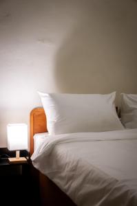 a bed with white sheets and a lamp on a table at Aayu Pantai - George Town, Penang in George Town +5 photos