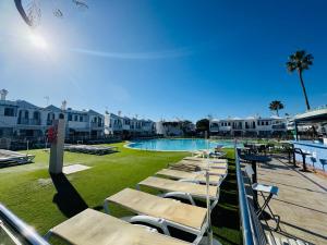 a row of chaise lounge chairs next to a swimming pool at Bungalow Gilly in Maspalomas