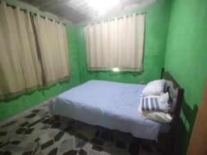 a bedroom with green walls and a bed with white sheets at Casa em Marataizes in Marataizes