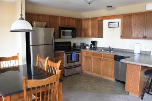 Una cocina con gabinetes de madera y un refrigerador de acero inoxidable. en 2 Bedroom Condo Duck Lake, en Eagle River