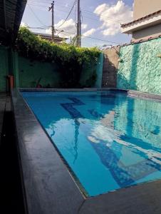a swimming pool with blue water in front of a building at Casa Água da Rocha in Itaguaí