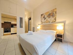 a bedroom with a large white bed and a kitchen at Viva Riviera Residence Marina Croisette in Cannes