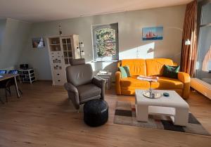 a living room with an orange couch and a chair at 2 Zimmer Appartement Ostseeblick in Boltenhagen