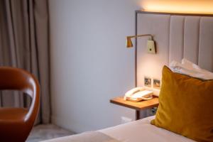 a hotel room with a bed with a yellow pillow and a phone at The Address Citywest in Citywest +27 photos