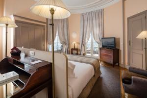 a hotel room with a bed and a desk and a television at Le Cavendish in Cannes