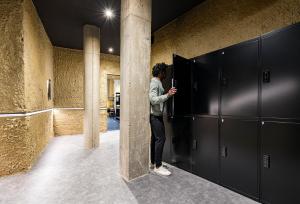 a man standing in a locker room looking at his cell phone at Apartamentos HEY U in Murcia