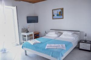 a white bedroom with a bed and a television at Rosemary Apartment in Promajna