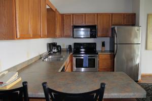 a kitchen with wooden cabinets and a stainless steel refrigerator at Wild Eagle Lodge, 2 bedroom 2nd floor condo, #216 in Eagle River