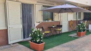 een patio met een parasol en een tafel en stoelen bij Casamemi San Lorenzo a due passi dalla Spiaggia in Reitani