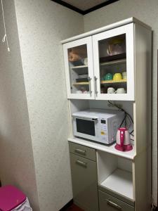 壹岐市一棟貸し民泊宿松山荘的厨房配有带微波炉的白色橱柜