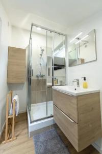 サン・テティエンヌにあるLa STÉPHANOISEのガラスのシャワーと洗面台を備えたバスルーム