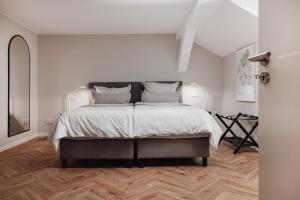 a white bedroom with a large bed and wooden floors at DOM Apartment III - modern & zentral mit kostenfreiem Parkplatz in Fulda