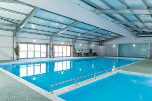 a large indoor swimming pool with blue water at The Delta Radiant in Leysdown-on-Sea