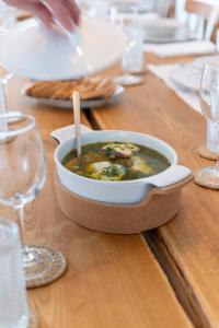 a bowl of soup sitting on a wooden table at Alàpega, Live Slow in Santa Susana +40 photos
