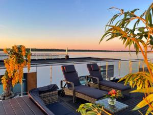 a deck with two chairs and a table on a boat at Floating Hideaway- Coco de Mer in Ribnitz-Damgarten