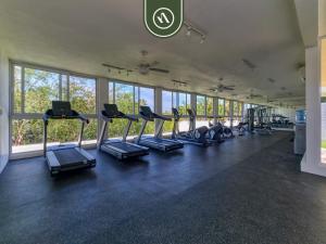 a gym with rows of treadmills in a room with windows at Brand New 1 BR Condo - Pool - Jacuzzi - Gym in Nuevo Nayarit