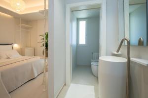 un bagno bianco con letto e vasca da bagno di Scirocco Boutique Eco Hotel a Torre Pali
