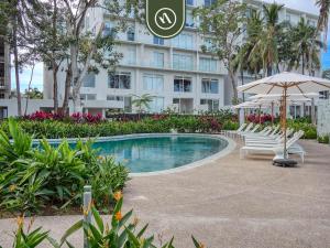 ein Swimmingpool mit Stühlen und einem Sonnenschirm und einem Gebäude in der Unterkunft Luxury 2 BR Condo Near Beaches - Pools - Gym in Nuevo Vallarta