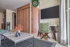 ein Wohnzimmer mit einem TV, einem Stuhl und einem Tisch in der Unterkunft Luxury 2 BR Condo Near Beaches - Pools - Gym in Nuevo Vallarta