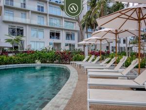 eine Reihe von Stühlen und Sonnenschirmen neben einem Swimmingpool in der Unterkunft Luxury 2 BR Condo Near Beaches - Pools - Gym in Nuevo Vallarta